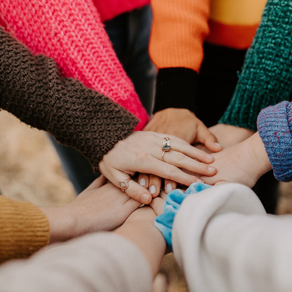 Close-up on the joined hands of a group of teenagers placed in a circle.